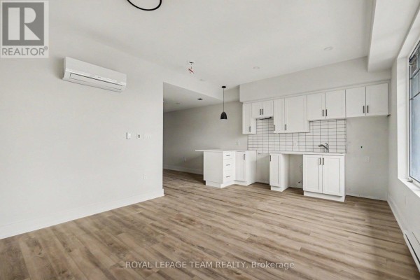 Small apartment kitchen with white cabinets and wood-look flooring. - 306 - 5874 County Rd #19 Road, North Grenville