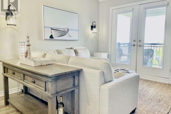Living room with a sofa, console table, and French doors leading to a balcony. - 306 - 7 Anchorage Crescent, Collingwood