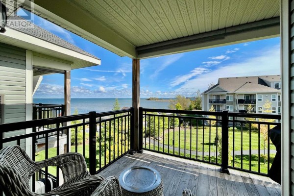 Balcony with wicker chairs and table, overlooking a body of water and buildings. - 306 - 7 Anchorage Crescent, Collingwood