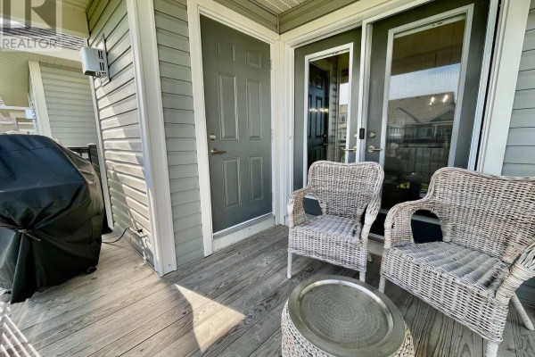 Outdoor balcony with wicker chairs, a small table, and a barbecue grill. - 306 - 7 Anchorage Crescent, Collingwood