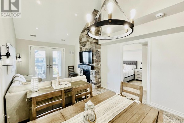 Dining area and living room with fireplace, showing a doorway to a bedroom. - 306 - 7 Anchorage Crescent, Collingwood