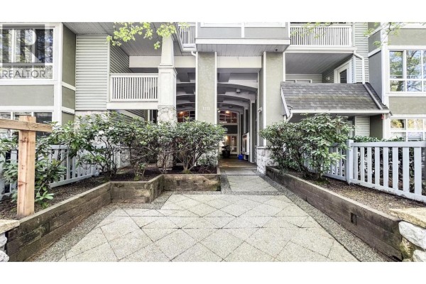 Covered entrance area with tiled floor, large windows, and seating. - 306 1111 Lynn Valley Road, North Vancouver