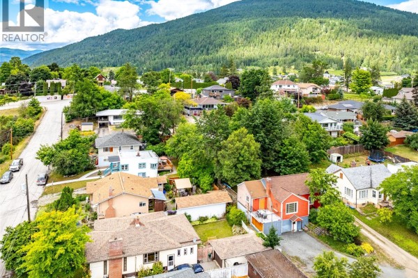 Aerial view of a suburban street with multiple houses and mature trees. - 306 11th  N Avenue, Creston