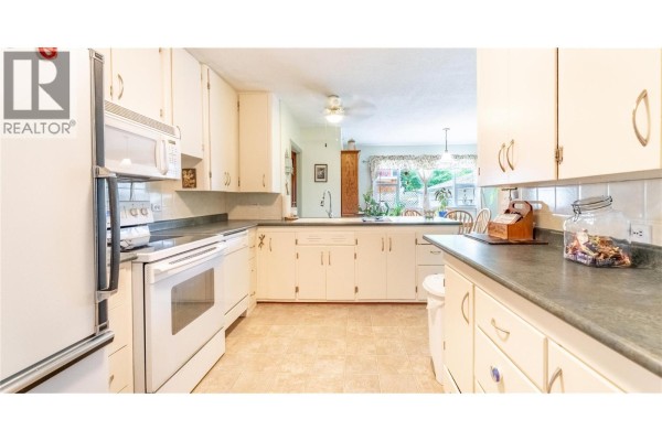 Kitchen with white cabinets, white appliances, and dark countertops. - 306 11th  N Avenue, Creston