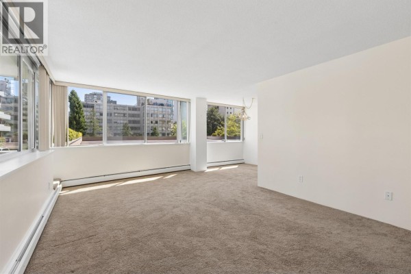 Living room with black sofa, green armchairs, coffee table, and city view windows. - 306 2055 Pendrell Street, Vancouver