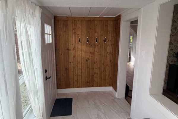 Entranceway with a white door, wood-paneled wall with coat hooks, and tiled flooring. - 306 47 Avenue W, Claresholm