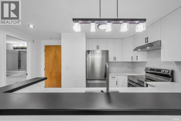 Bedroom with hardwood floors, large window, and view of trees and balcony. - 306 6833 Village Grn, Burnaby