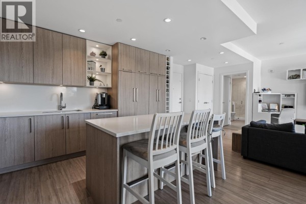 Modern kitchen with wood cabinetry, quartz island, and island seating. - 306 707 E 3rd Street, North Vancouver