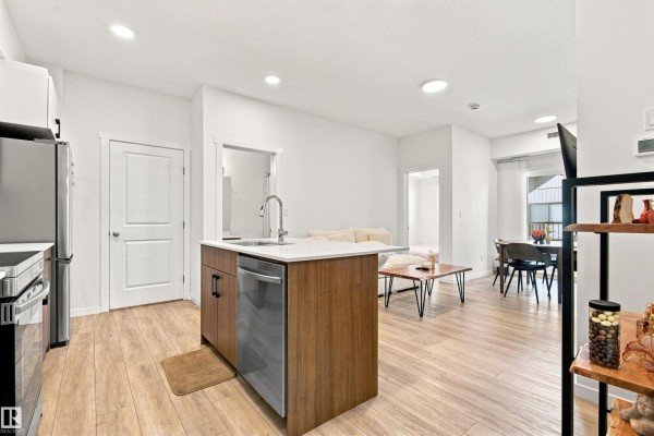 Open concept living area with kitchen island, stainless steel appliances, and living room. - #306 9223 228 St Nw Nw, Edmonton