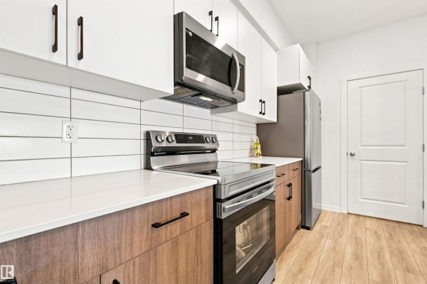 Kitchen with white and wood cabinets, stainless steel appliances, and white tile backsplash. - #306 9223 228 St Nw Nw, Edmonton