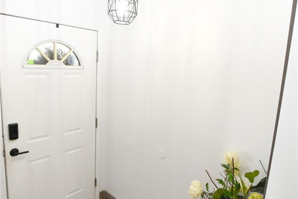 White front door with a half-round window and smart lock, adjacent to a plain wall. - 306 O'regan Crescent, Saskatoon