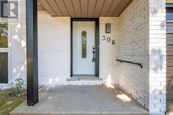 Close-up of the front entrance with a wooden door, brick exterior, and porch lights. - 306 Sekura Street, Cambridge