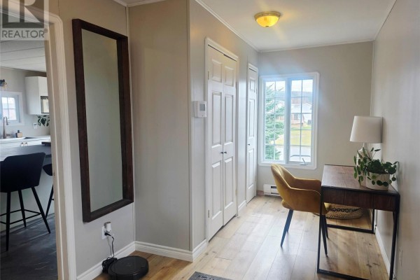 Interior hallway with wood floors, a large mirror, and a small desk area. - 3069 Walsh River Road, Labrador City