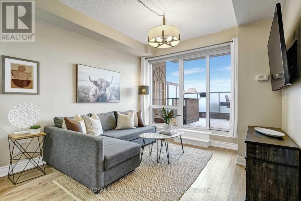 Living room with a sectional sofa, coffee table, rug, and large sliding doors. - 306a - 9088 Yonge Street, Richmond Hill