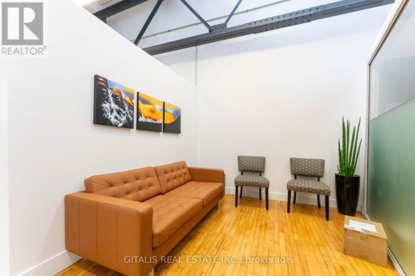 Waiting area with a brown leather sofa, two patterned chairs, and artwork. - 306b - 219 Dufferin Street, Toronto