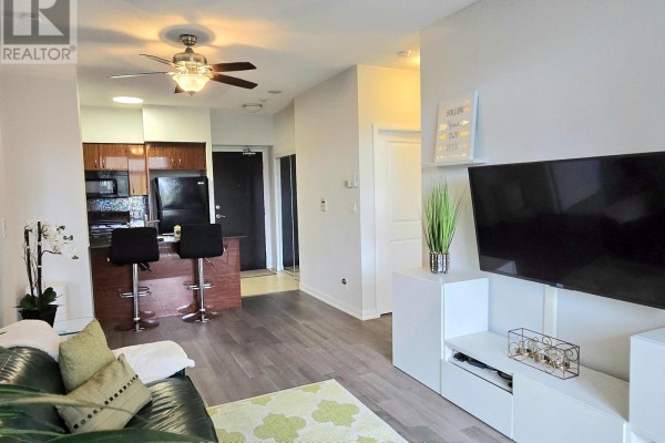 Living room with TV, kitchen with bar stools, and hallway door. - 307 - 5791 Yonge Street, Toronto