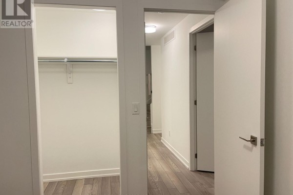Empty walk-in closet with shelf and hanging rod, opening to a hallway with white doors. - 307 - 8 Walder Lane, Richmond Hill