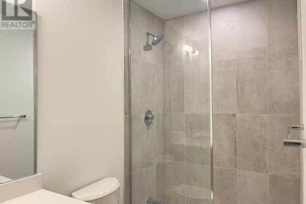Shower stall with light grey tiles, chrome fixtures, and a glass door in a bathroom. - 307 - 8 Walder Lane, Richmond Hill