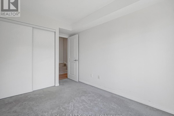 Bedroom with grey carpet, white walls, large sliding closet, and open door. - 307 - 90 Orchid Place Drive, Toronto