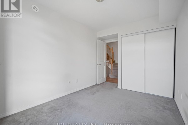 Bedroom with grey carpet, white walls, large sliding closet, and open door to stairs. - 307 - 90 Orchid Place Drive, Toronto