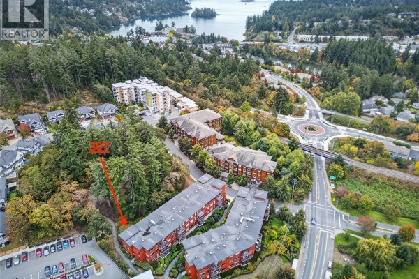 Aerial view of apartment buildings on a wooded hillside near a highway intersection. - 307 170 Nursery Hill Dr, View Royal