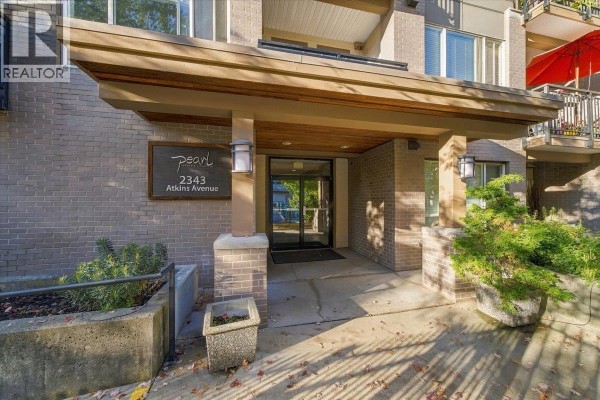 Entrance to the Pearl apartment building at 2343 Atkins Avenue with brick facade and wooden overhang. - 307 2343 Atkins Avenue, Port Coquitlam