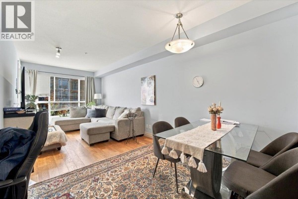 Living and dining area with a glass-top dining table, chairs, sectional sofa, and hardwood flooring. - 307 2343 Atkins Avenue, Port Coquitlam