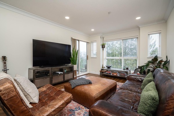 Living area showcasing a TV unit, leather seating, and decorative plants near the window. - 307 5499 203 Street, Langley