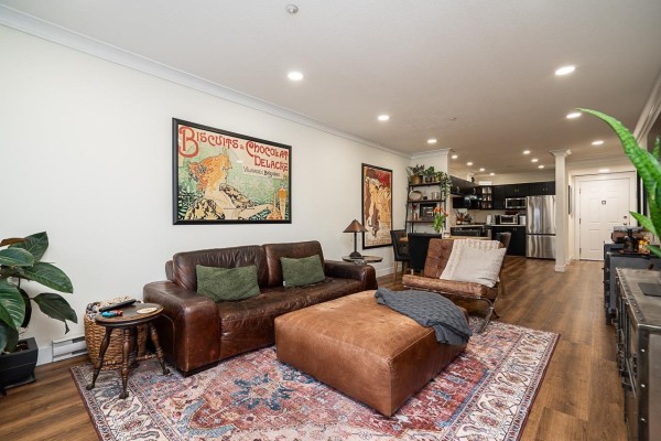 Stylish living room with artwork, a brown ottoman, and a mix of seating options. - 307 5499 203 Street, Langley