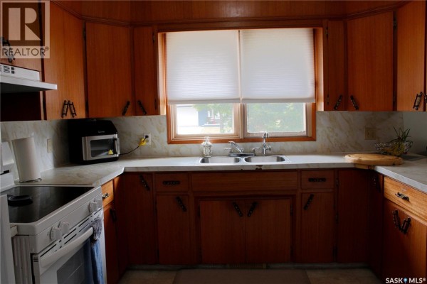 Kitchen with light wood cabinets, white countertop, double sink, and appliances. - 307 Centennial Avenue, Kipling