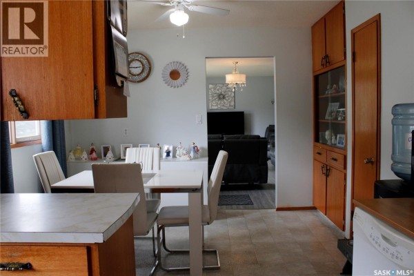 Kitchen and dining area with light wood cabinets, white table and chairs, and view into living room. - 307 Centennial Avenue, Kipling