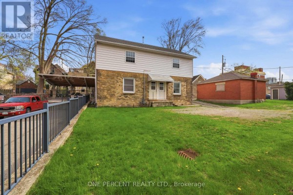 Rear exterior of a two-story building with white siding and stone lower level. - 307 Central Avenue, London East