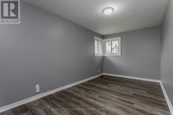 Bedroom with grey walls, vinyl plank flooring, and two windows - 307 Dunsmure Road Hamilton