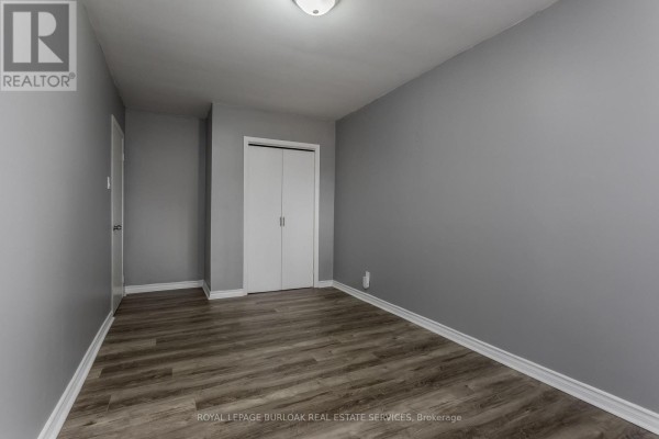 Hallway with closet doors and wood-look laminate flooring - 307 Dunsmure Road Hamilton