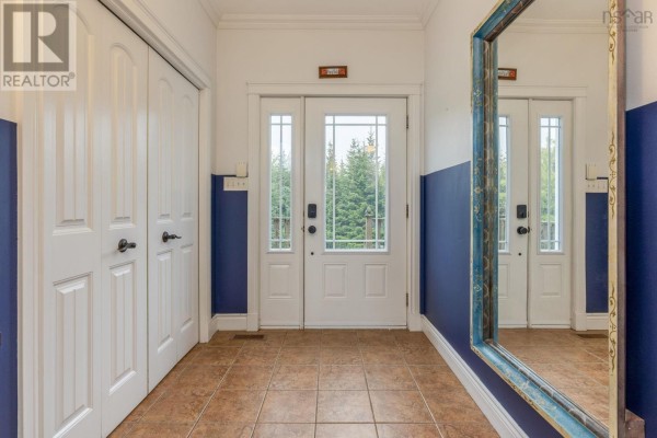 Interior view of a front entryway with tiled floor, white double doors, and a blue accent wall. - 307 Leslie Road, East Lawrencetown