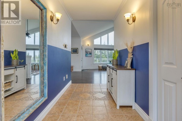 Interior view of a hallway with tiled floor, white cabinets, large mirror, and doorway to living area. - 307 Leslie Road, East Lawrencetown