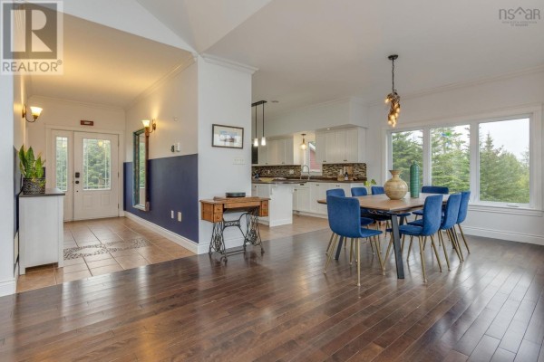 Interior view of a dining area with blue chairs and a large window, adjacent to the kitchen. - 307 Leslie Road, East Lawrencetown