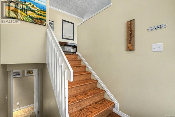 Interior view of a staircase with light beige walls and wooden steps. - 3071 Shamrock Pl, Nanaimo
