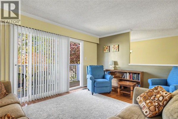 Living room with two blue armchairs, a sofa, and sliding glass doors to a balcony. - 3071 Shamrock Pl, Nanaimo