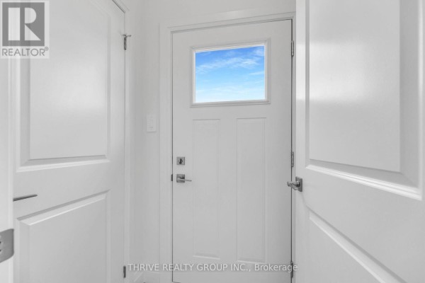 Empty bedroom with white walls and carpet, featuring three windows with a suburban view. - 3076 Buroak Drive, London North
