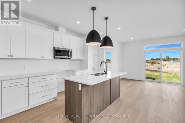 Modern kitchen with white cabinets, a grey island, stainless steel appliances, and pendant lights. - 3076 Buroak Drive, London North