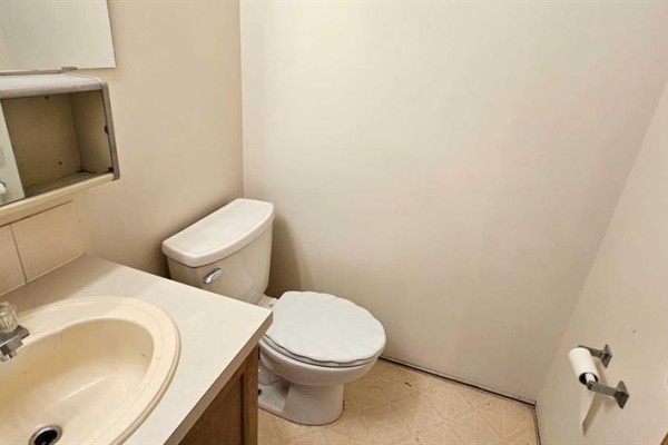 A half bathroom with a toilet, sink, and toilet paper holder. - 308, 5015 51 St Street, Taber