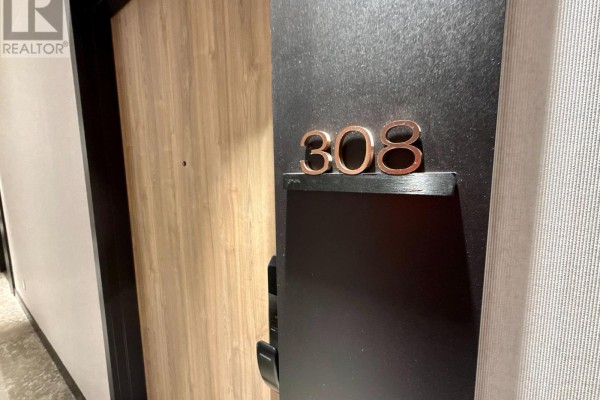 Close-up of the unit number "308" on a dark apartment door. - 308 - 1 Fairview Road E, Mississauga