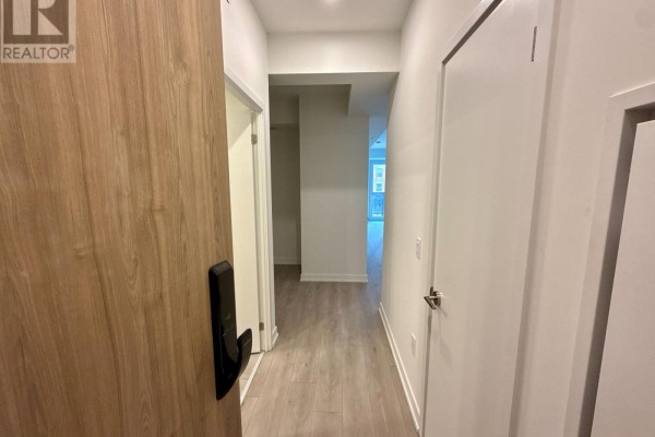 View down a white hallway with light wood floors and doors. - 308 - 1 Fairview Road E, Mississauga