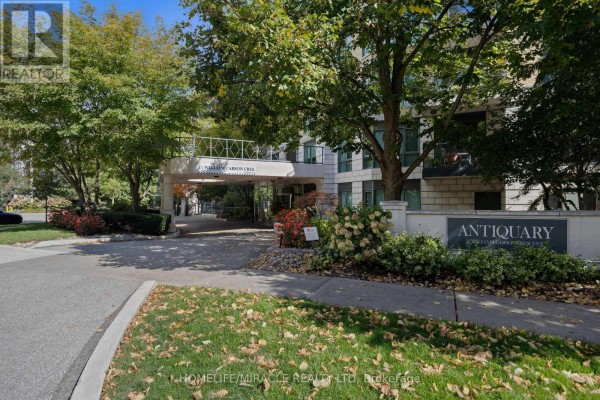 Entrance drive to a stone and brick apartment building with "Antiquary" signage. - 308 - 11 William Carson Crescent, Toronto