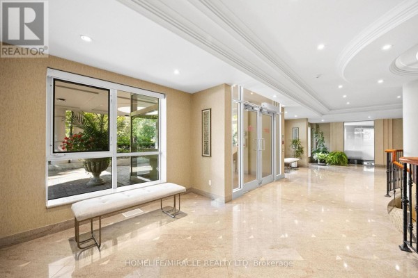 Bright, spacious lobby with marble floors, a bench, glass doors, and decorative wallpaper. - 308 - 11 William Carson Crescent, Toronto