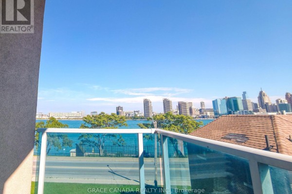 Balcony view from an apartment showing a river, cityscape, and trees with glass railings. - 308 - 1225 Riverside Drive W, Windsor
