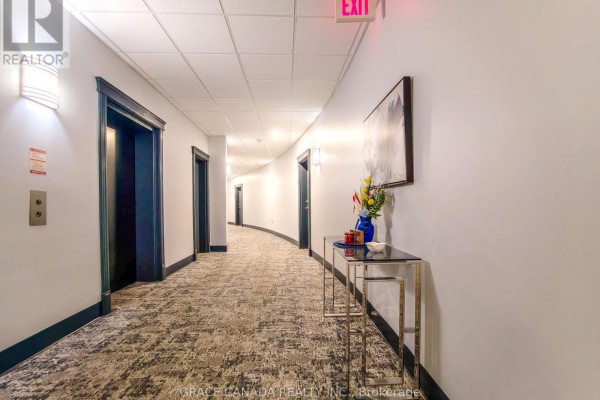 Hallway of an apartment building with a curved layout, carpeted floor, and elevators. - 308 - 1225 Riverside Drive W, Windsor