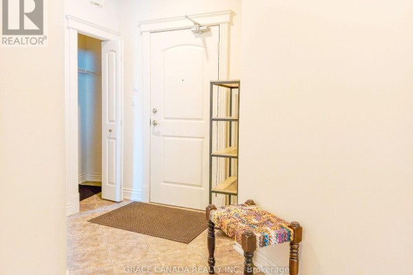 Entrance hallway inside an apartment with a white door, tile floor, and decorative bench. - 308 - 1225 Riverside Drive W, Windsor