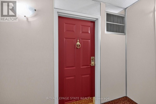 Red apartment door with brass hardware and a peephole, set in a cream-colored hallway. - 308 - 150 Wilson Street W, Hamilton